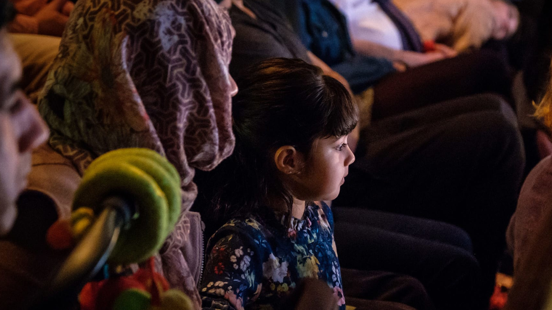A mother and daughter. The daughter is sat on her mother's knee.